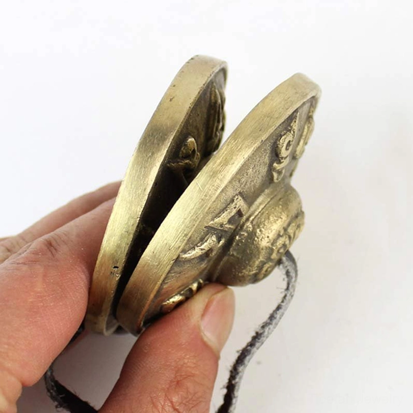 Side profile close-up view of tibetan tingsha bell showing curved shape and leather connecting cord