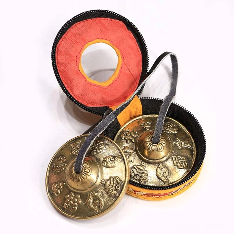 Tibetan tingsha cymbals eight auspicious symbols design with protective carrying pouch on white background
