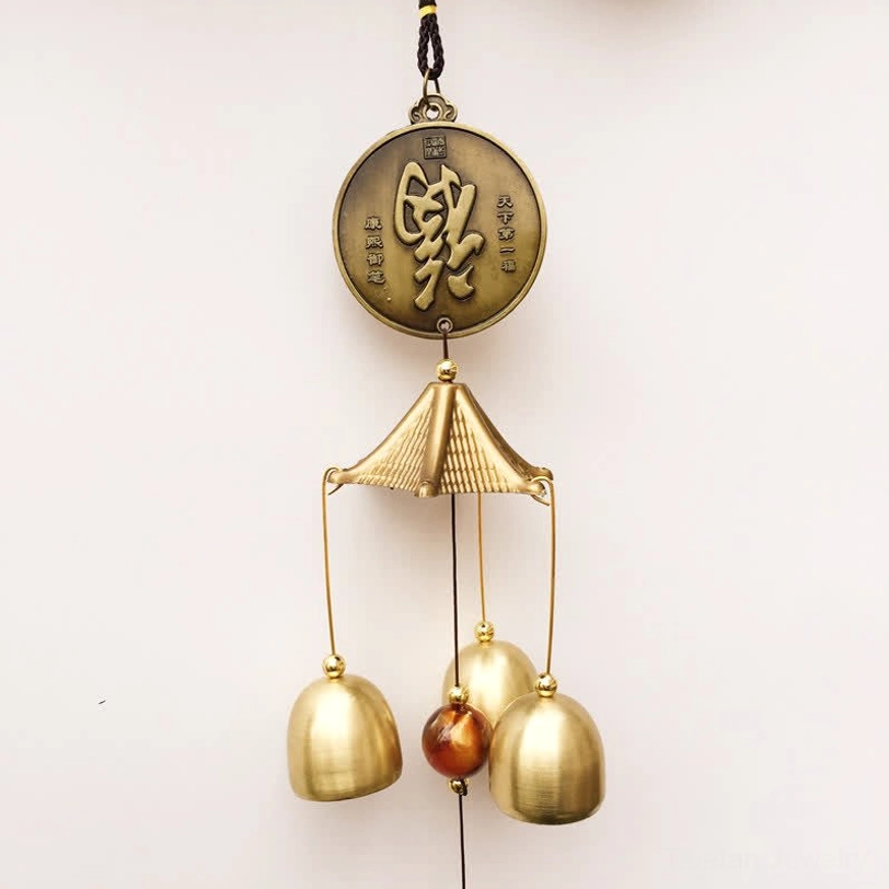 Tiny Chinese bronze wind chime with small coin and brass bells foliage background