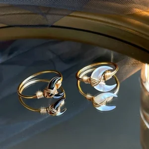 Black and white Tridacna moon blessing rings comparison flat lay showing both styles side-by-side with gold metal settings