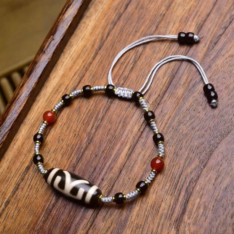 Turquoise and Dzi bead protection bracelet flat lay with turquoise stones, gold accents, and sliding knot closure on wooden surface