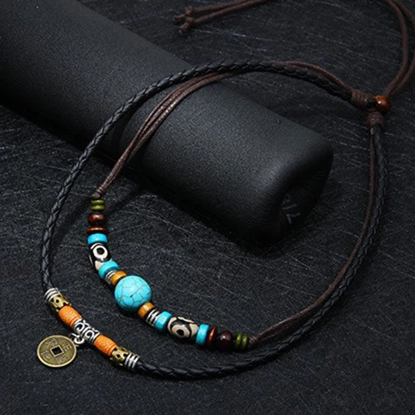 Layered turquoise Dzi bead necklace close-up showcasing braided leather, mixed tribal beads and antique coin charm on dark background