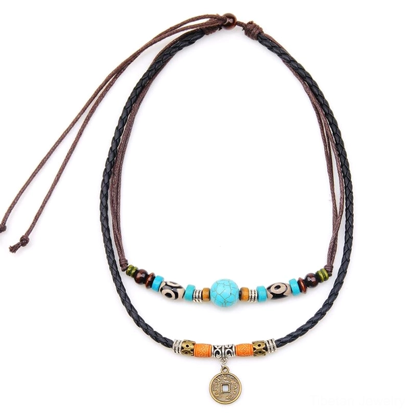 Turquoise Dzi bead layered protection necklace with braided leather cord and antique coin pendant displayed on white background