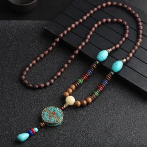 Turquoise Dzi prayer wheel necklace with synthetic turquoise bead and wenge wood beads on dark wooden background