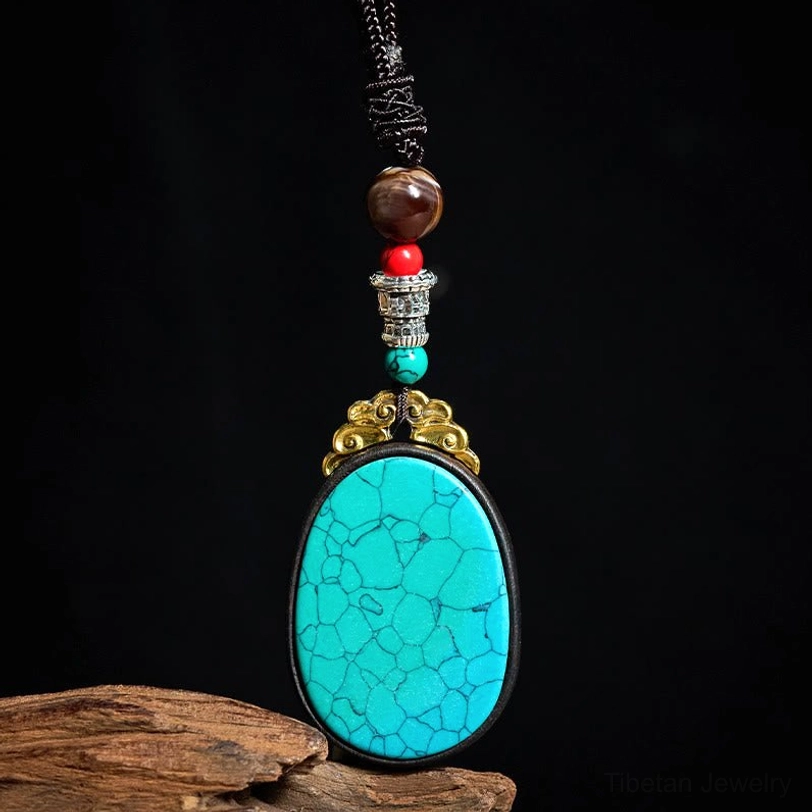 Turquoise blue ebony wood tribal pendant necklace with braided cord, hanging on textured fabric background
