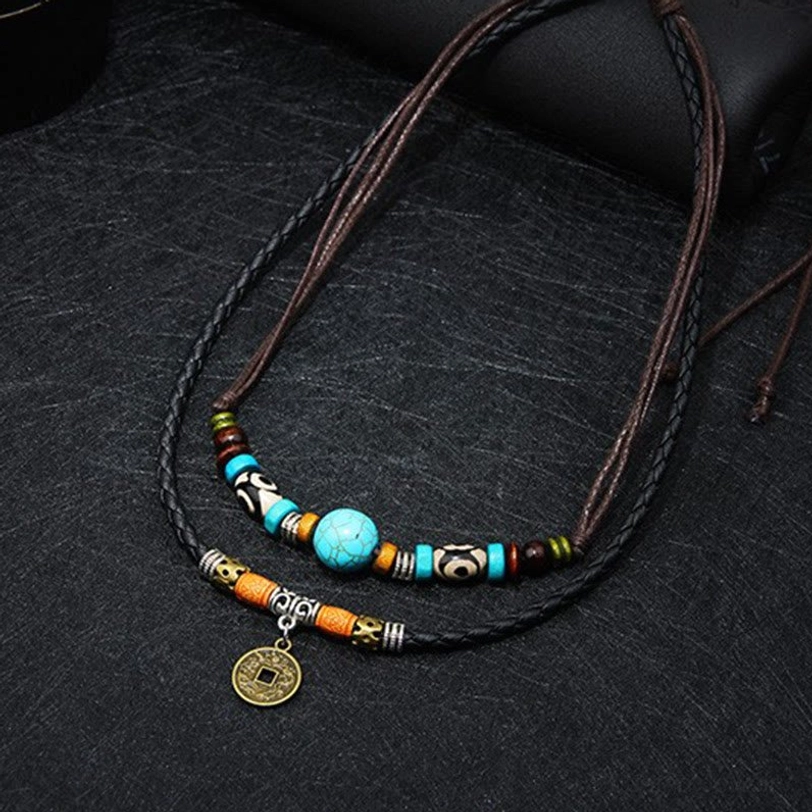 Turquoise ethnic protection necklace flat lay displaying smooth and braided leather cord design with decorative coin charm