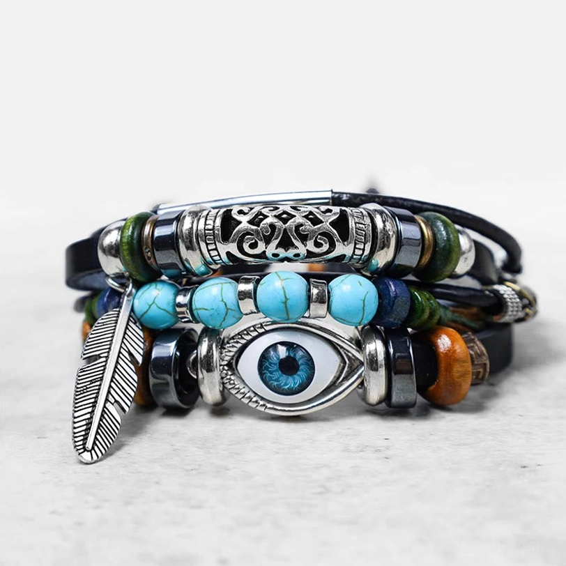 Layered leather turquoise evil eye bracelet with silver filigree accents and feather pendant flat lay