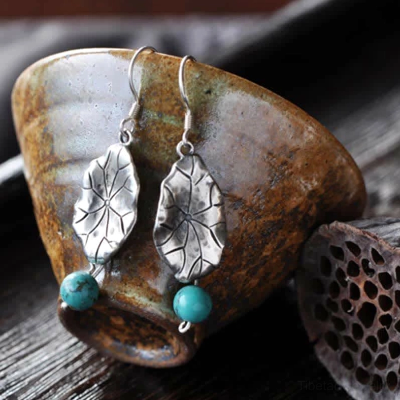 Matching pair of turquoise lotus leaf drop earrings displayed with ceramic teacup and lotus pod prop