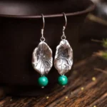 Sterling silver lotus leaf turquoise drop earrings hanging display on wooden table with dark ceramic bowl