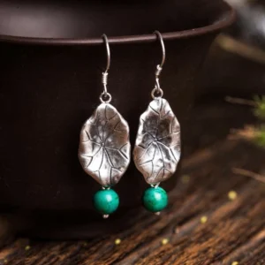Sterling silver lotus leaf turquoise drop earrings hanging display on wooden table with dark ceramic bowl