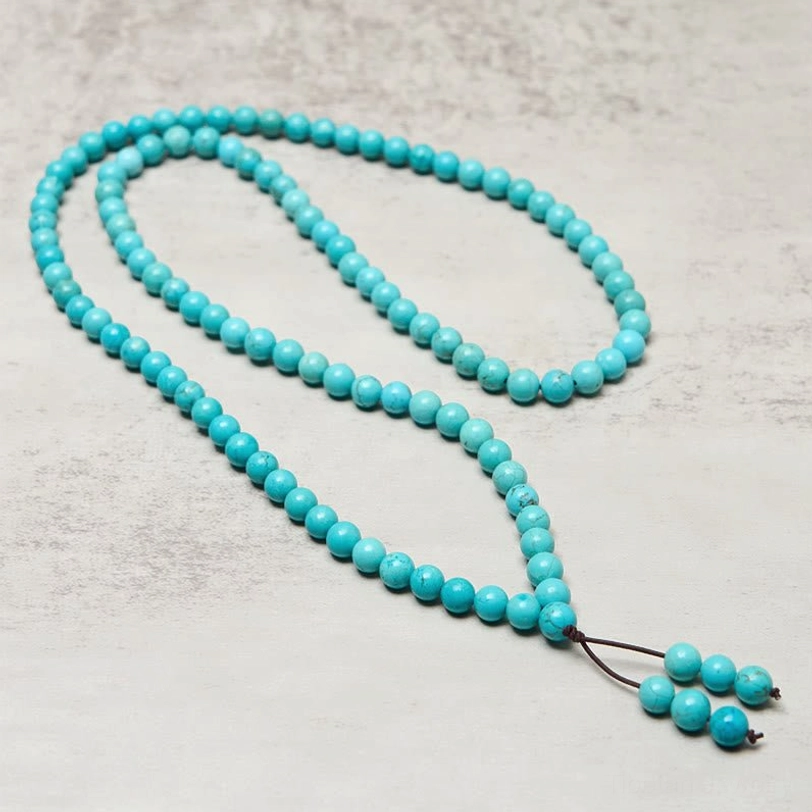 Full 108-bead turquoise mala strand stretched out with brown tassel - complete necklace length display for meditation