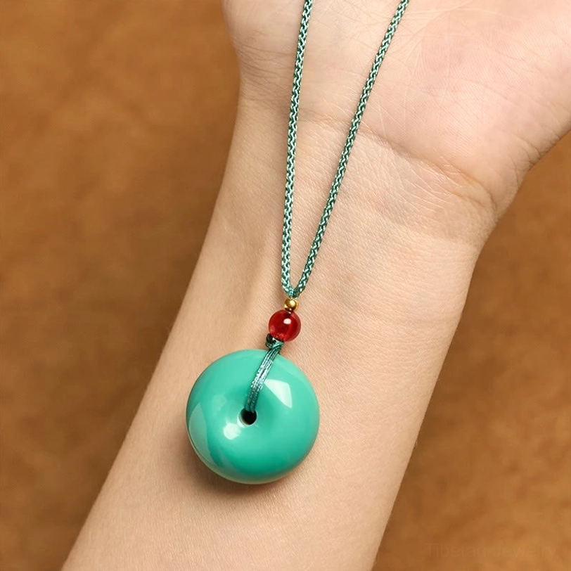 Turquoise peace buckle necklace worn on wrist showing how pendant fits on body with teal cord and polished turquoise stone