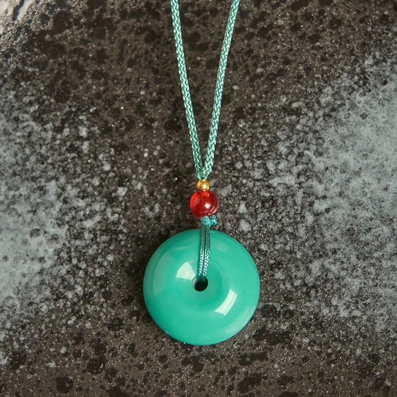 Close-up front view of turquoise peace buckle pendant showing smooth circular design with gold spacer and red accent bead