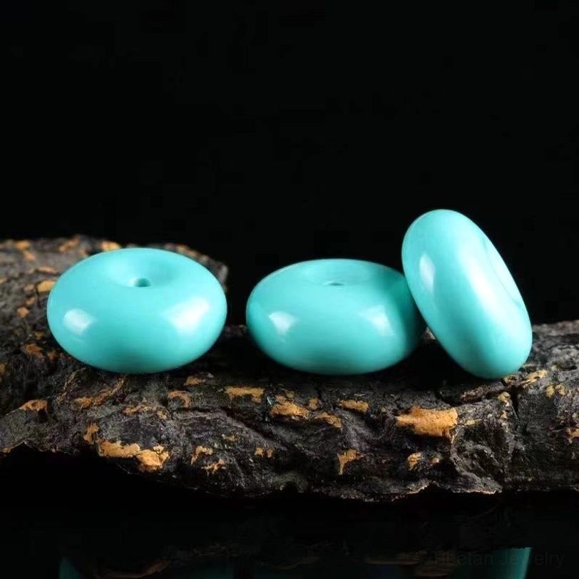 Three loose turquoise peace buckles top-down view showing smooth matte blue-green circular pendants on dark stone surface