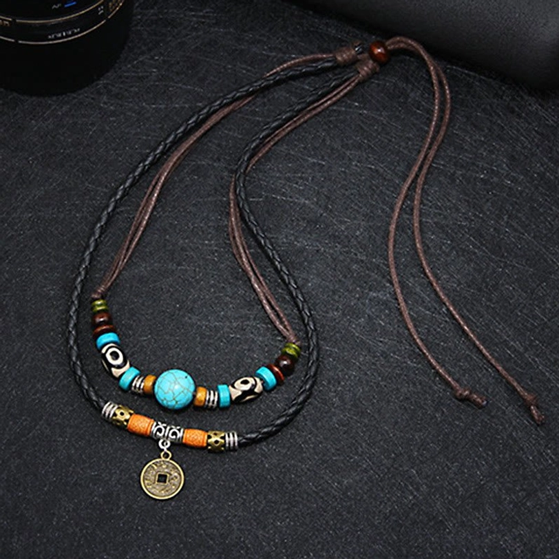 Side overhead view of turquoise protection necklace showing adjustable tie straps and layered leather cord construction on dark fabric