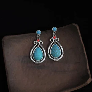 Pair of vintage turquoise teardrop dangle earrings flat lay on brown wooden tray, symmetrical design