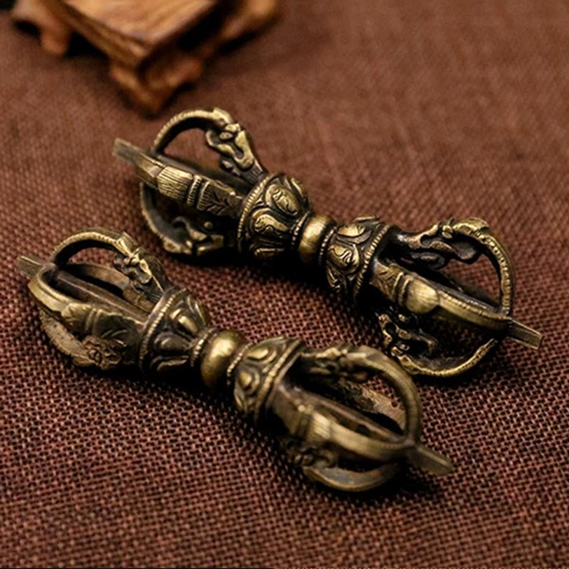 Two matching five-prong Tibetan Vajra Dorje in antique bronze finish displayed flat, showing identical carved details and aged patina