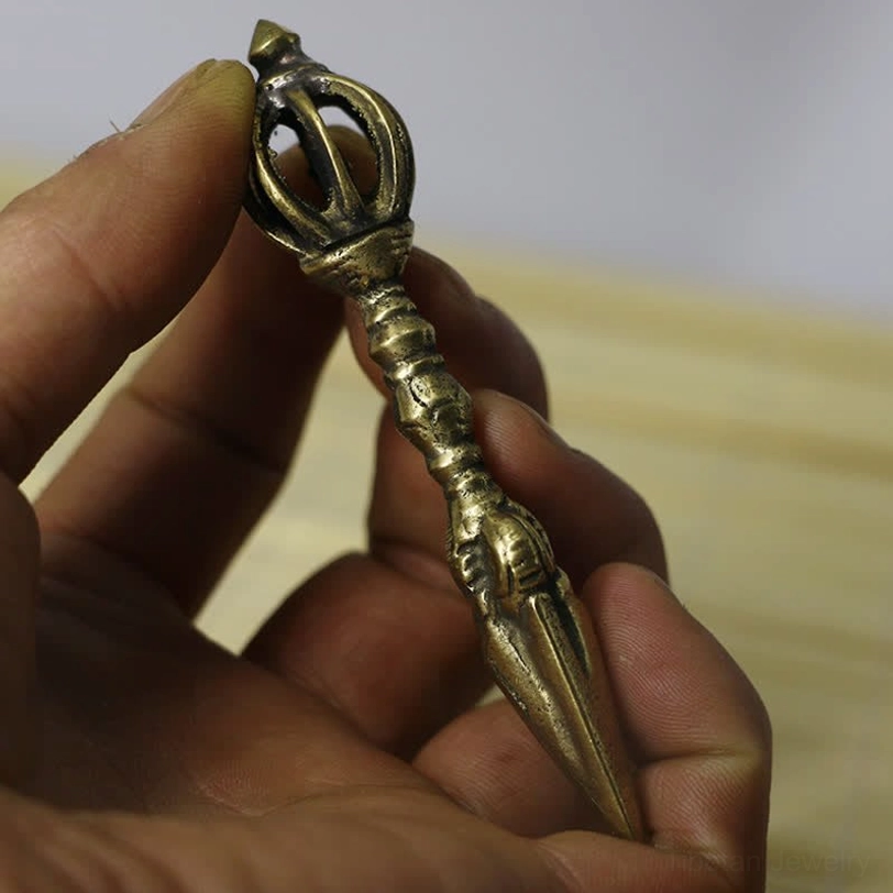 Tibetan nine-strand vajra dorje held in hand showing size and antique brass metal craftsmanship of ritual meditation tool