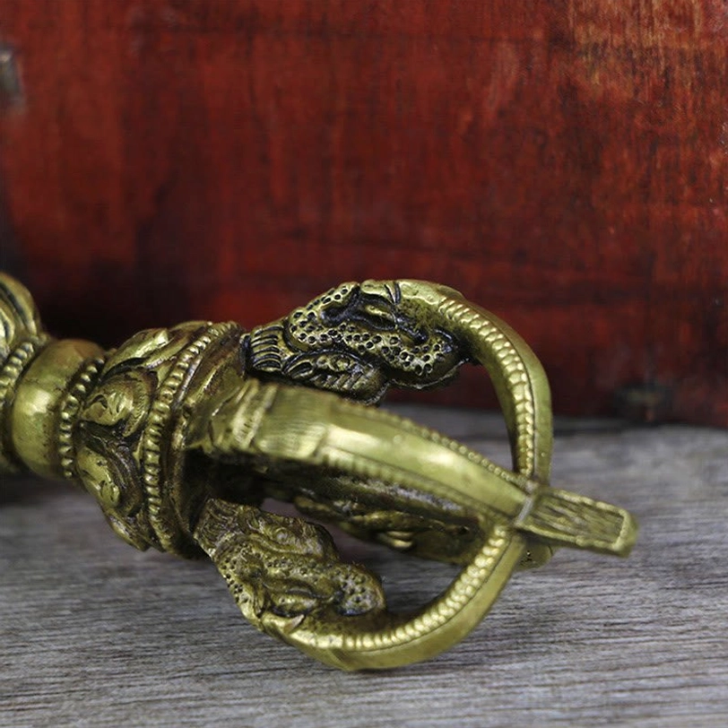 Close-up low angle view of handmade copper vajra dorje showing relief carved prong heads and intricate bronze tone metalwork texture details