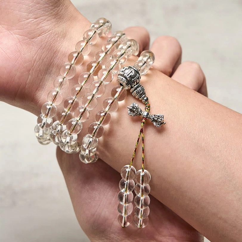 Vajra mala bracelet worn on wrist with silver pendant and colored tassel detail