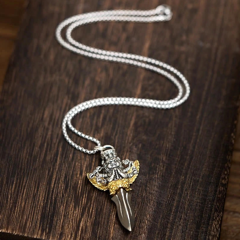 Tibetan Vajra pendant necklace flat lay with coiled silver curb chain, showing complete jewelry piece with deity and dagger design