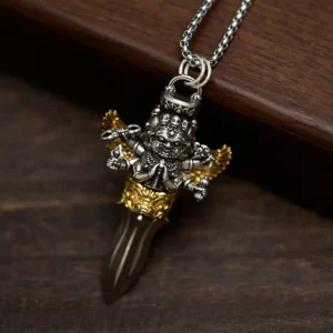 Tibetan Vajra pendant necklace side view showing detailed multi-arm deity sculpture and sharp vajra dagger with silver-gold finish