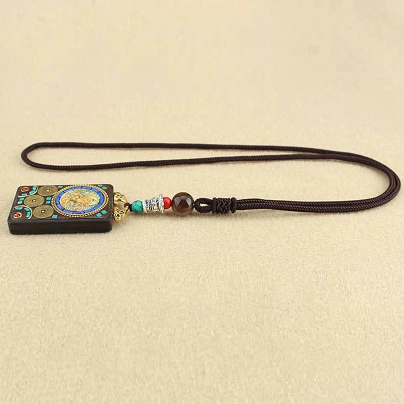 Tibetan Five Gods of Wealth thangka pendant laid flat on beige background showing side profile and artwork details