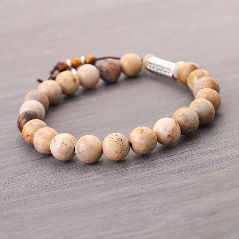 Handmade Tibetan prayer bracelet overhead flat lay showing smooth round weathered stone beads and silver charm