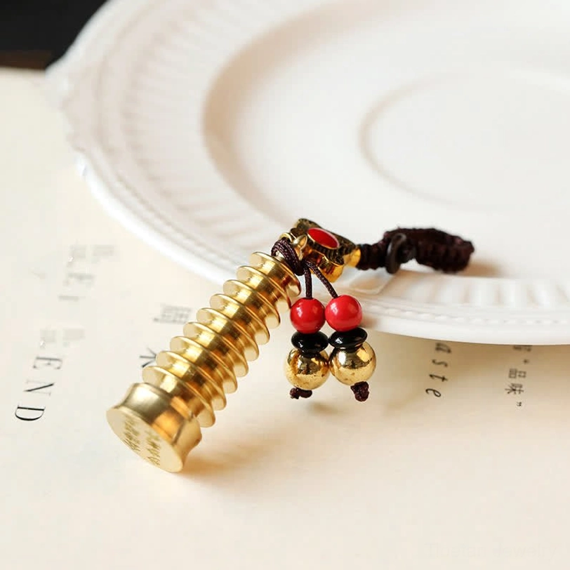 Wenchang Pagoda brass keychain with multi-layered tower design and bead decorations on white plate, academic success symbol