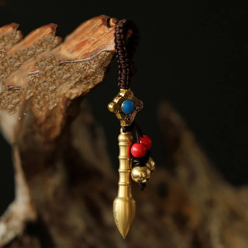 Wenchang Pen brass keychain featuring inlaid turquoise bead and red bell tassels, hanging on wooden background, scholarly wisdom charm