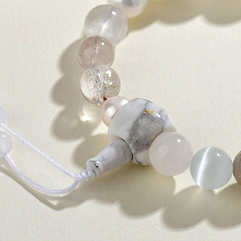 Close-up macro shot of white agate pearl bracelet guru bead section with carved stone beads and woven tassel detail