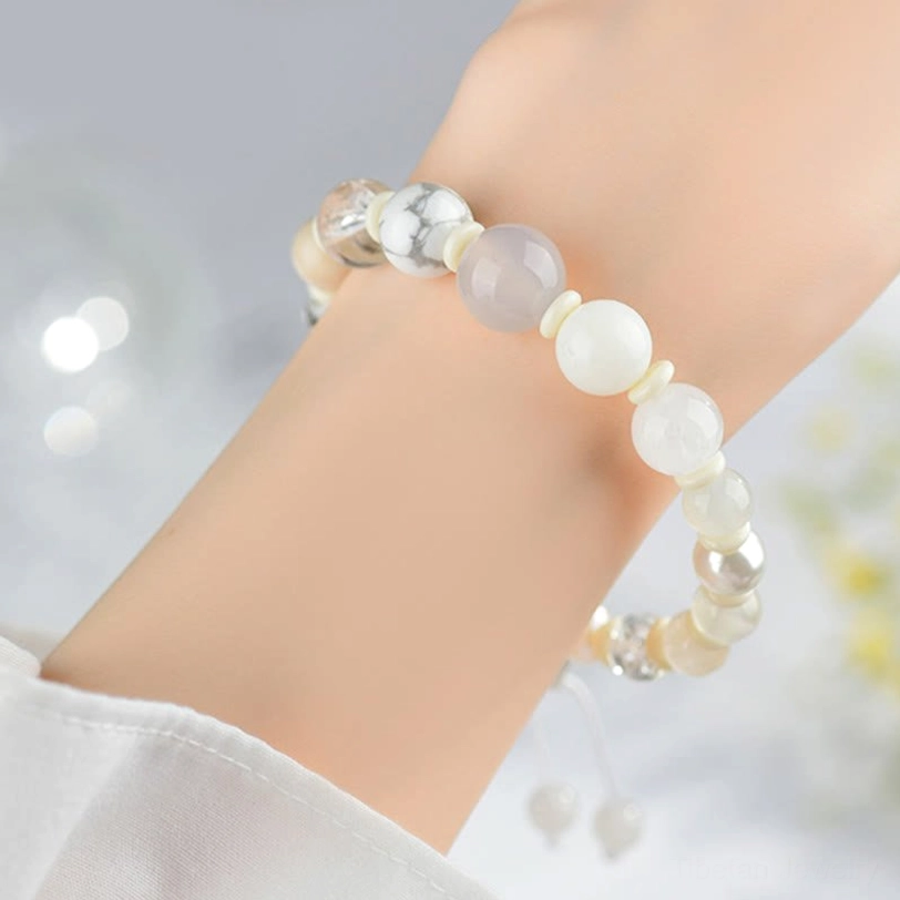 White agate pearl harmony bracelet on wrist - side profile view showing fit and natural gem bead details with blurred floral backdrop