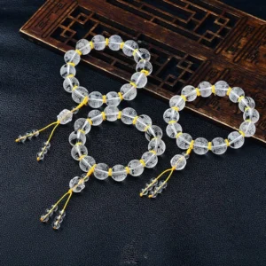 Collection of white crystal Buddhist prayer bracelets with Heart Sutra engravings displayed on carved wooden panel with yellow tassels