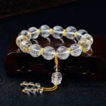 White crystal half demon half Buddha heart sutra bracelet with engraved beads on wooden display holder, shown from oblique angle