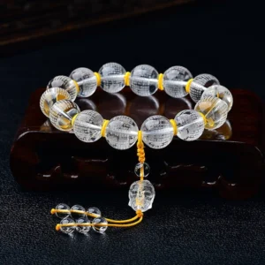 White crystal half demon half Buddha heart sutra bracelet with engraved beads on wooden display holder, shown from oblique angle