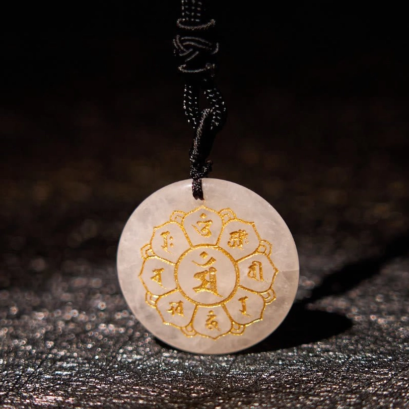 White crystal Om Mani Padme Hum pendant with lotus flower Sanskrit pattern on dark glittery background