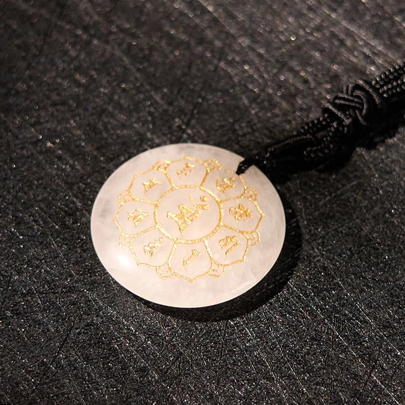 White crystal tibetan pendant close-up showing detailed Sanskrit mantra engraving