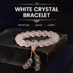 White crystal Om Mani Padme Hum meditation bracelet with gold tassel, displayed on wooden surface showing clear quartz beads