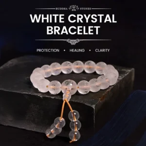 White crystal Om Mani Padme Hum meditation bracelet with gold tassel, displayed on wooden surface showing clear quartz beads