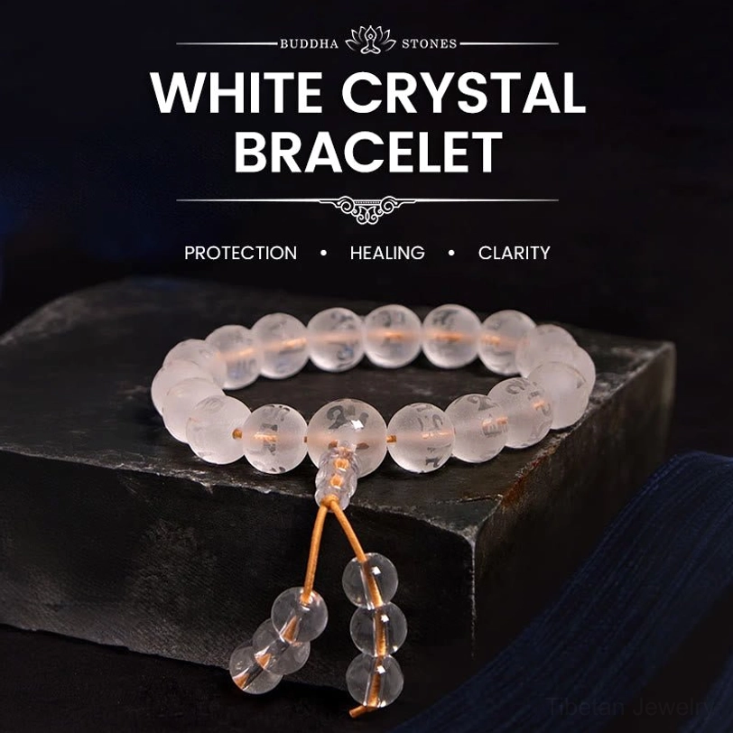 White crystal Om Mani Padme Hum meditation bracelet with gold tassel, displayed on wooden surface showing clear quartz beads