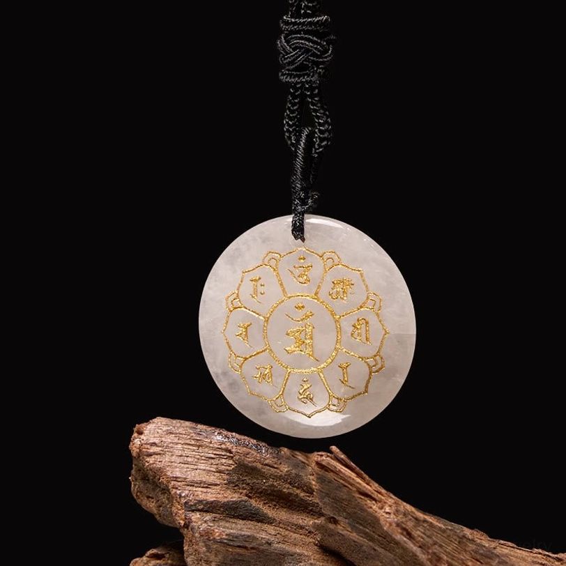 White crystal quartz Om Mani Padme Hum pendant with golden Sanskrit engraving on wooden background