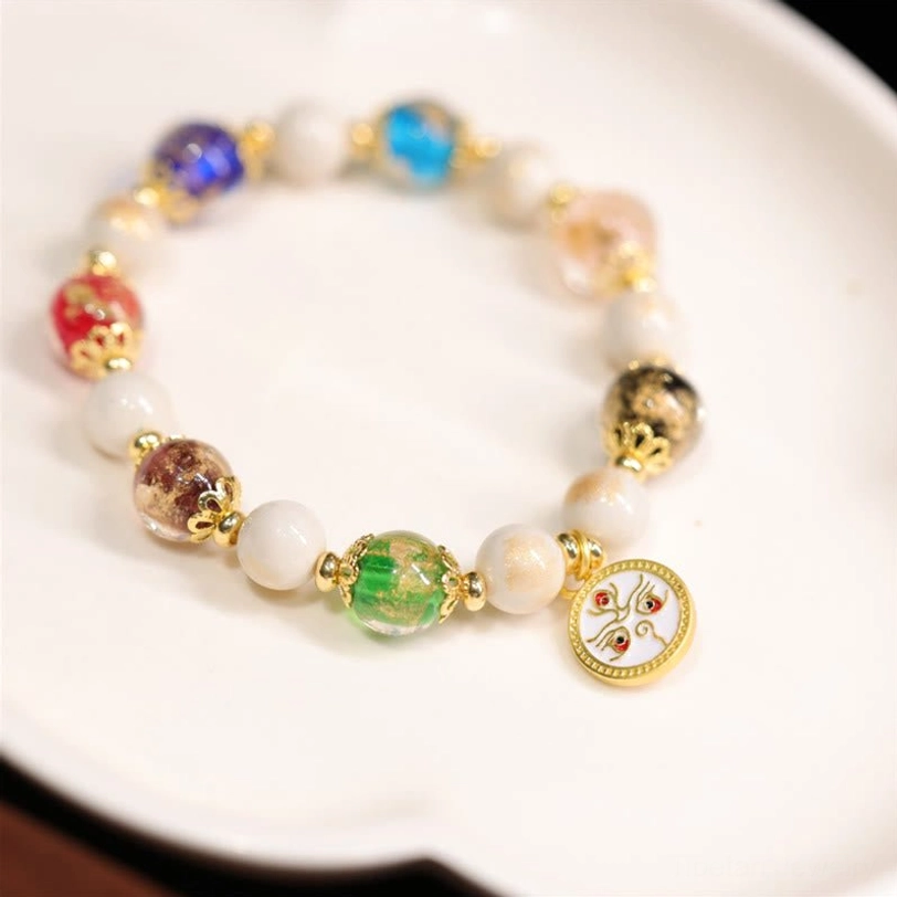 White God of Wealth Tibetan blessing bracelet with white enamel Avalokiteshvara charm pendant and liuli glass beads close-up detail