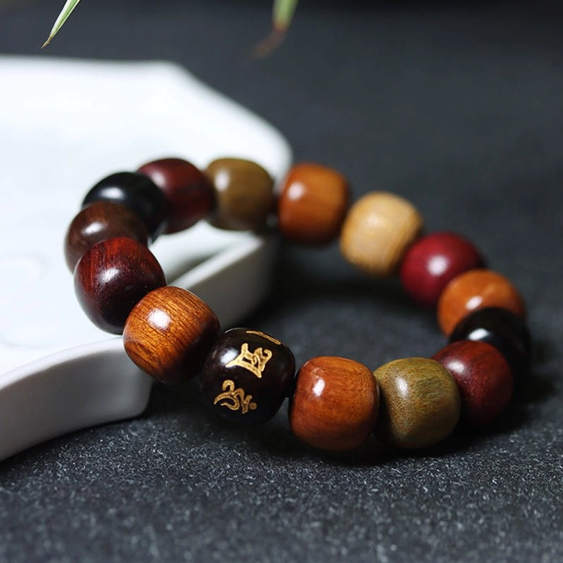 Detailed view of light brown carved wooden bead among mixed natural wood beads on prayer bracelet