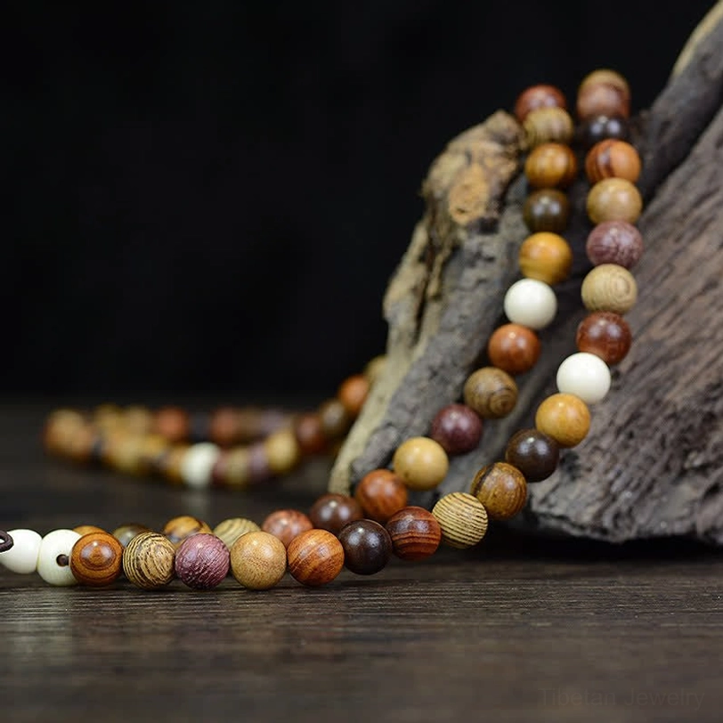 Long natural wood prayer mala strand draped on weathered driftwood with warm brown and deep tone beads
