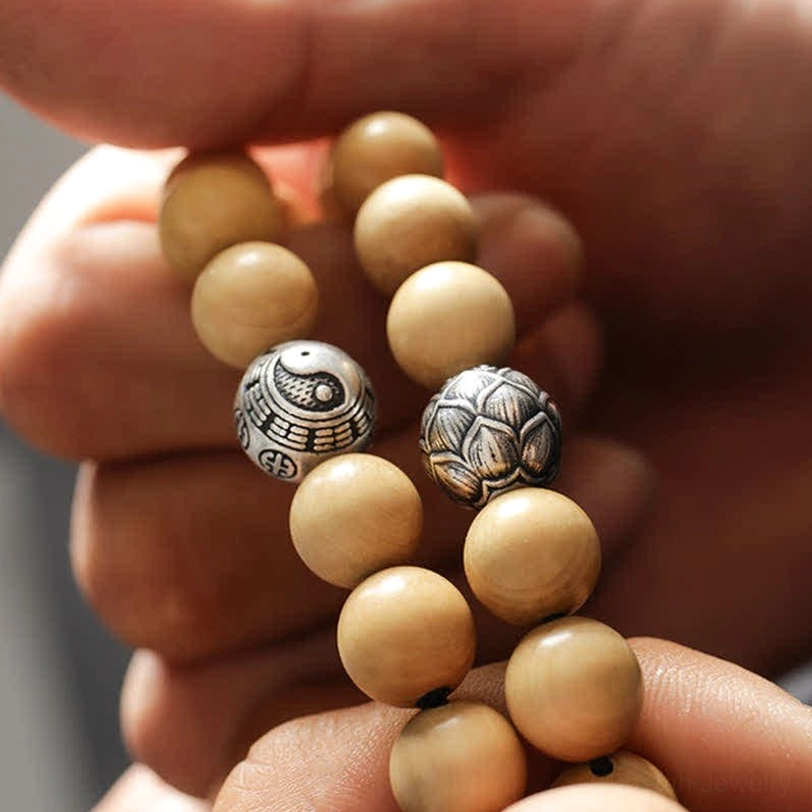 Wooden beaded bracelet with engraved silver spacers - hand holding detail shot of multiple designs