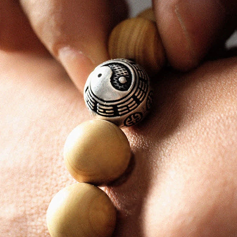 Macro close-up of wooden bracelet on wrist skin - detailed view of large engraved bagua spacer bead