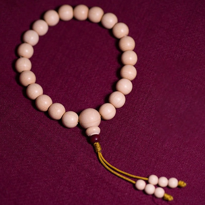 Top-down perspective of 21-bead Abelia Biflora mala showing symmetrical round bead arrangement and traditional tassel on dark red meditation cloth