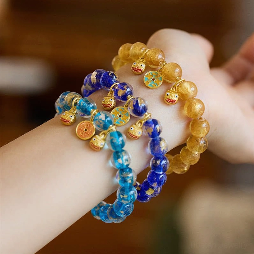 Yellow crystal and blue glass Pi Xiu fortune bracelets with gold metal beads, front wrist view