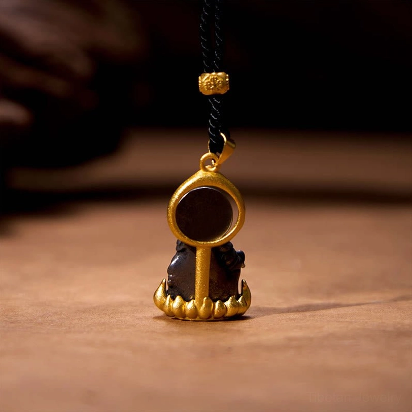 Tibetan Jambhala pendant back view showing gold frame, dark circular back panel, and black hand-braided cord with decorative gold bead