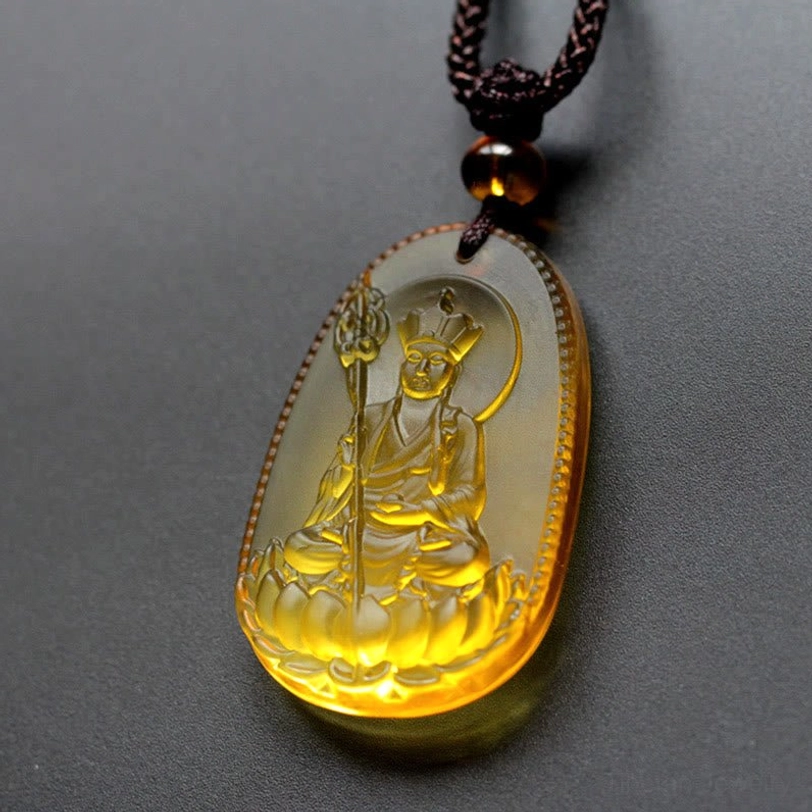 Amber yellow Ksitigarbha Buddha Liuli crystal pendant with oval shape, seated Bodhisattva on lotus with halo, brown braided cord with amber bead accent